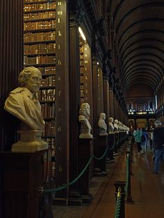 many busturines and bookshelves are lined up along the wall in this library