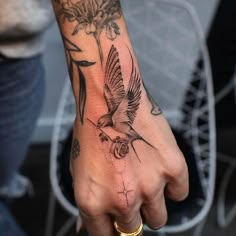 a person's hand with a bird and flower tattoo on it