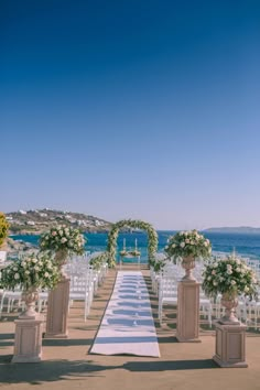 an outdoor ceremony setup with white flowers and greenery on the aisle, overlooking the ocean