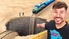 a man standing in front of a train track with a blue and yellow train coming out of it