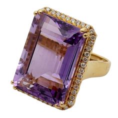 Vintage Amethyst Diamond Cocktail Ring   A dramatic statement piece brimming with vintage glamour, this amethyst and diamond cocktail ring is a true showstopper.  A deep violet-purple amethyst, weighing a substantial 28.73 cts takes centre stage, surrounded by a sparkling halo of Brilliant cut diamonds totalling 0.55 cts. The 18ct gold setting features a deep basket work gallery and a substantial gold shank, ensuring a comfortable fit on the finger.  This majestic ring, weighing 13.7 gms, sits h Glamour Vintage, Diamond Cocktail Ring, Centre Stage, Diamond Cocktail Rings, Violet Purple, Vintage Glamour, Cocktail Ring, Purple Amethyst, Brilliant Cut Diamond