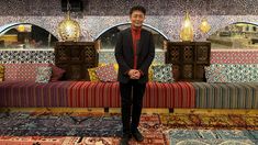 a man standing in front of a colorful couch with mirrors on the wall behind it