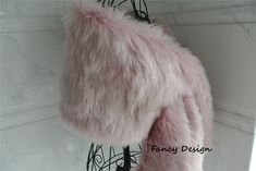 a pink fur coat hanging on a wall next to a white marble counter top with the word fancy design written below it