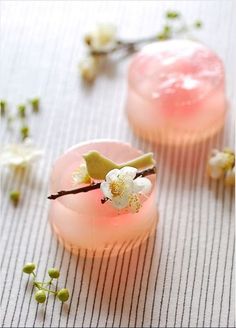 two pink cups with flowers on them sitting on a table next to some buds and twigs