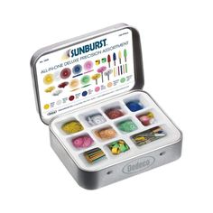 an open tin filled with different colored crayons and other art supplies on a white background