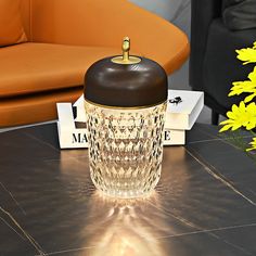 a glass jar sitting on top of a table next to a yellow flower and some books