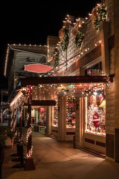 a street with christmas lights and decorations on the side of it's buildings at night