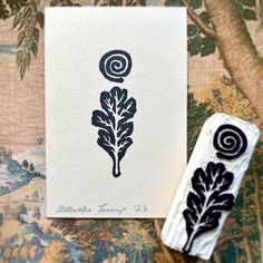 two rubber stamps sitting on top of a piece of paper next to a painting with leaves and spirals