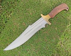 a knife that is laying on the ground in the grass with it's blade out