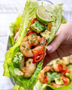 a person is holding a lettuce wrap with shrimp and avocado on it