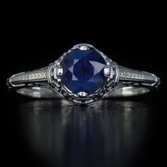 an antique style ring with a blue stone in the center and diamond accents around it