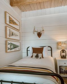 there is a bed in the room with pictures on the wall and deer head above it