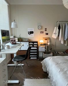 a white bed sitting next to a desk with a computer on top of it in a bedroom