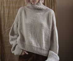 a woman with pink hair wearing a sweater