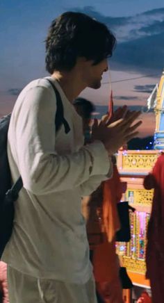 a man standing in front of a temple with his hands together and other people around him