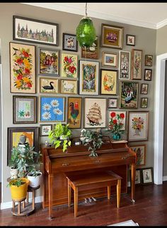 a living room filled with lots of framed pictures on the wall above a grand piano