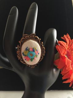 a close up of a person's hand wearing a ring with flowers on it