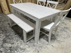 a white table with two chairs and a bench in front of some wood planks