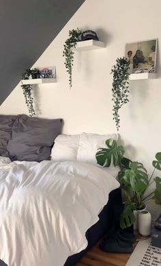 a bed sitting under a slanted ceiling next to two planters on either side of the bed