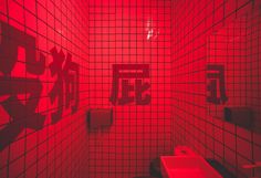 a bathroom with red lighting and tiled walls