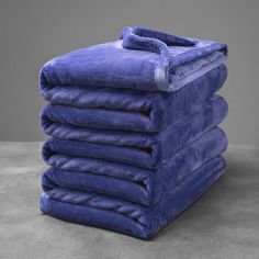 a stack of blue towels sitting on top of a gray floor next to each other