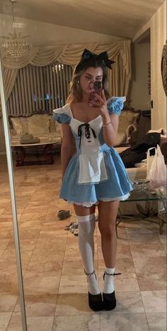 a woman taking a selfie in front of a mirror wearing a blue and white dress