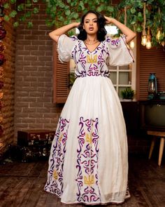 This stunning Habesha Kemis is a true work of art, featuring a mesmerizing Tilf pattern and the traditional elegance of the Shimena style. The intricate Tilf embroidery is expertly crafted, showcasing the beauty and richness of Ethiopian design. The flowing skirt and elegant neckline of the Kemis are designed to be both comfortable and flattering, making it the perfect choice for any special occasion. The vibrant colors of the Tilf pattern are both eye-catching and regal, adding to the overall b Eritrean Dress, Habesha Dress, Habesha Kemis, Mesmerizing Beauty, Wedding Dress Chiffon, Dresses Chiffon, Cultural Events, Purple Pattern, Flowing Skirt