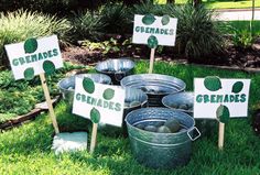 several metal buckets filled with green eggs sitting on top of grass next to signs