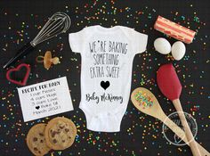 a baby's bodysuit, cookie and other items are laid out on a table