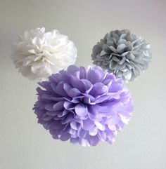 three purple and white flowers are hanging from the ceiling in front of a white wall