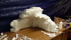 a large white sculpture sitting on top of a wooden table next to a blue tarp