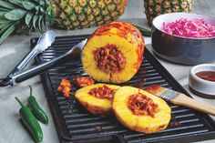 pineapples and other foods are on a grill with utensils next to them