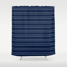 a blue shower curtain with white dots and lines on the bottom, in front of a gray background