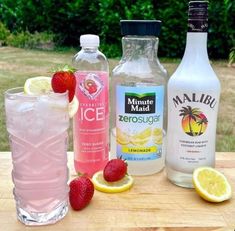 three different types of drinks on a table with strawberries and lemons next to them