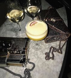 a table topped with glasses of wine and a purse next to a glass of wine