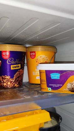 three ice creams are sitting on top of a shelf in a refrigerator, and one is filled with peanut butter