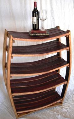 a wine bottle and glass sitting on top of a wooden shelf next to a white wall