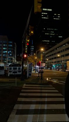 a city street at night with traffic lights on and buildings in the backround