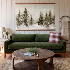 a living room with a green couch and coffee table in front of a painting on the wall