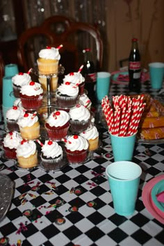 a table topped with cupcakes covered in white frosting and red striped paper straws