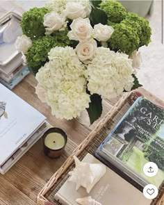 a table topped with books and flowers next to a vase filled with white hydrangeas