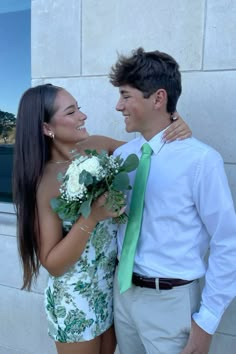 a man and woman standing next to each other with flowers in front of their faces