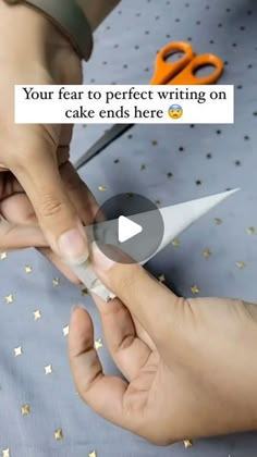 someone is cutting paper with scissors on top of the cake and confetti sprinkles