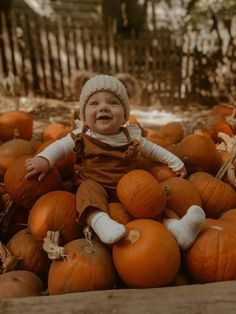 a baby sitting in a pile of pumpkins