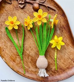 crocheted daffodils are arranged on a wooden platter