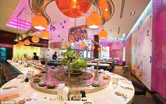 the restaurant is decorated with colorful lights and decorations on the ceiling, along with round tables