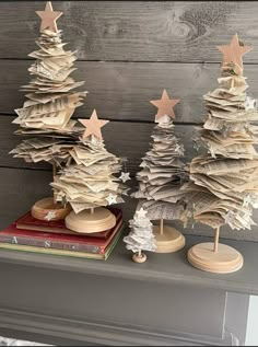 three small wooden christmas trees sitting on top of a mantle next to books and magazines