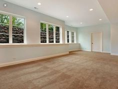 an empty living room with large windows and carpet