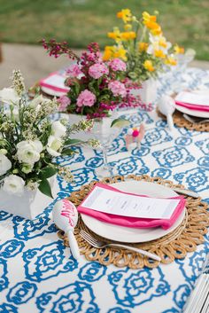 the table is set with pink and white plates, napkins, and flower centerpieces