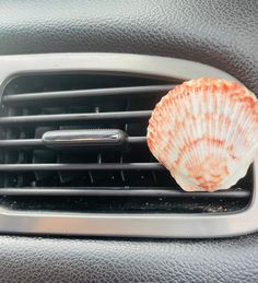 an orange shell sitting on top of a car air conditioner in front of a window